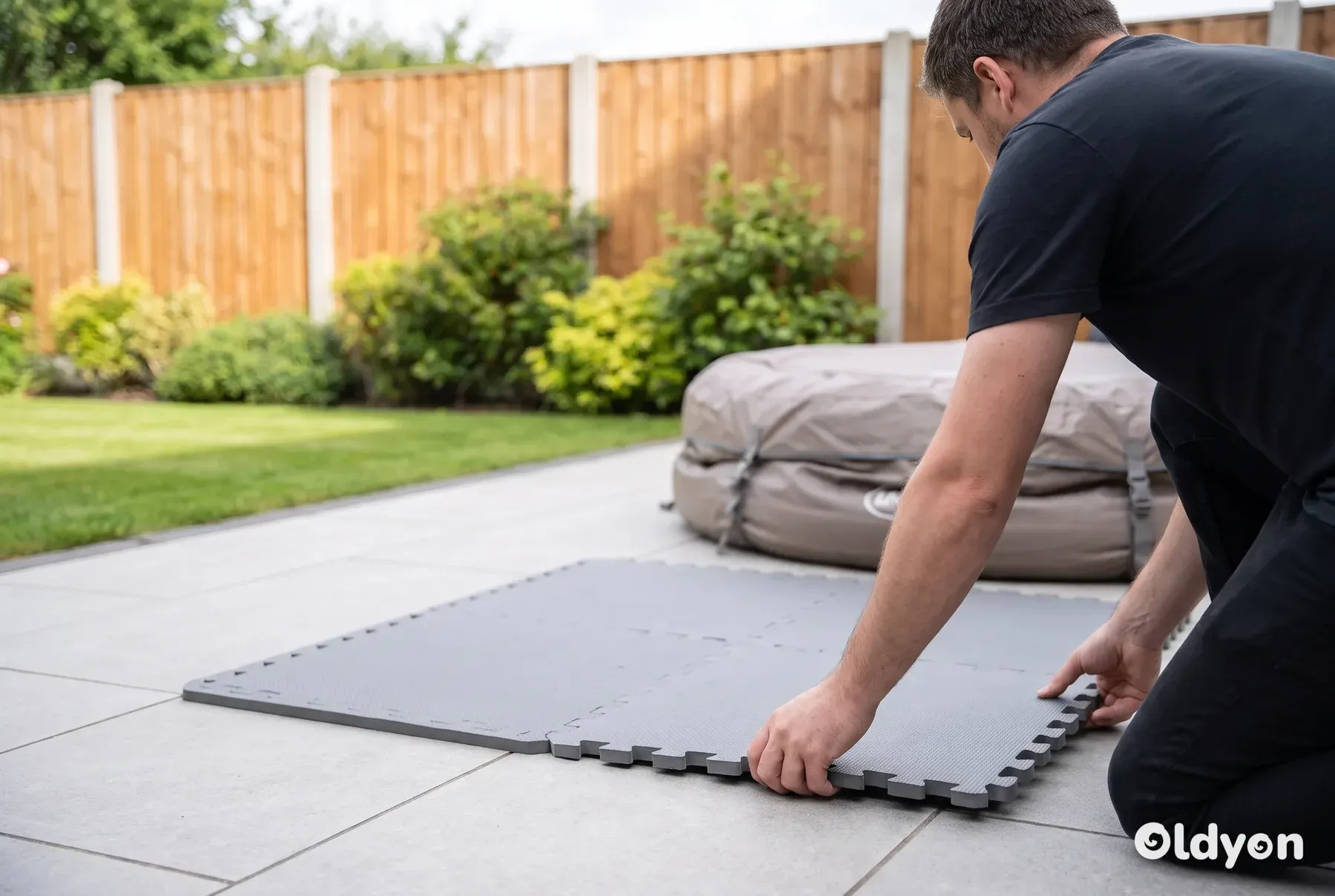 Grey interlocking foam pad laid on a level paved patio in a British garden, ready for an inflatable hot tub