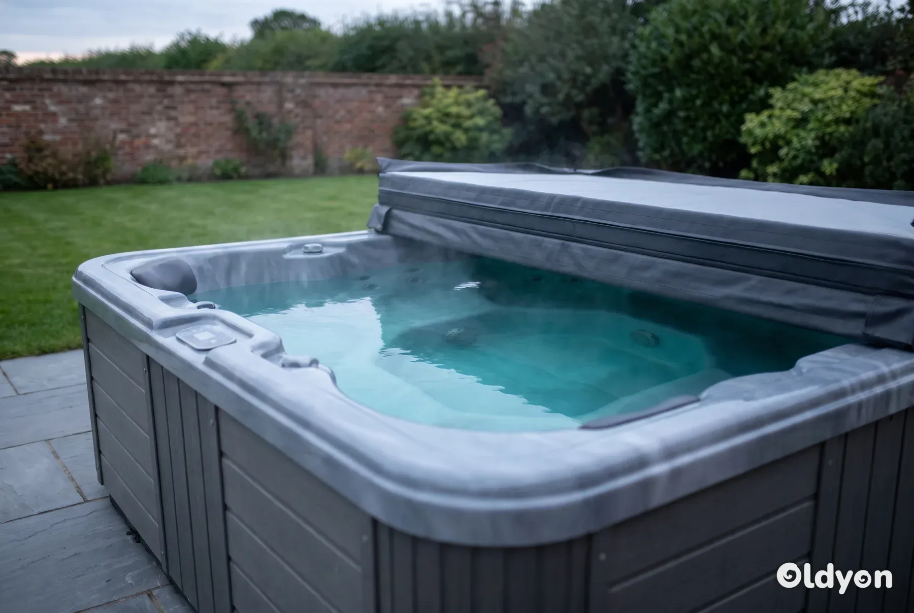 Spa rigide avec sa couverture repliée sur une terrasse en pierre dans un jardin britannique à la lumière du début de soirée