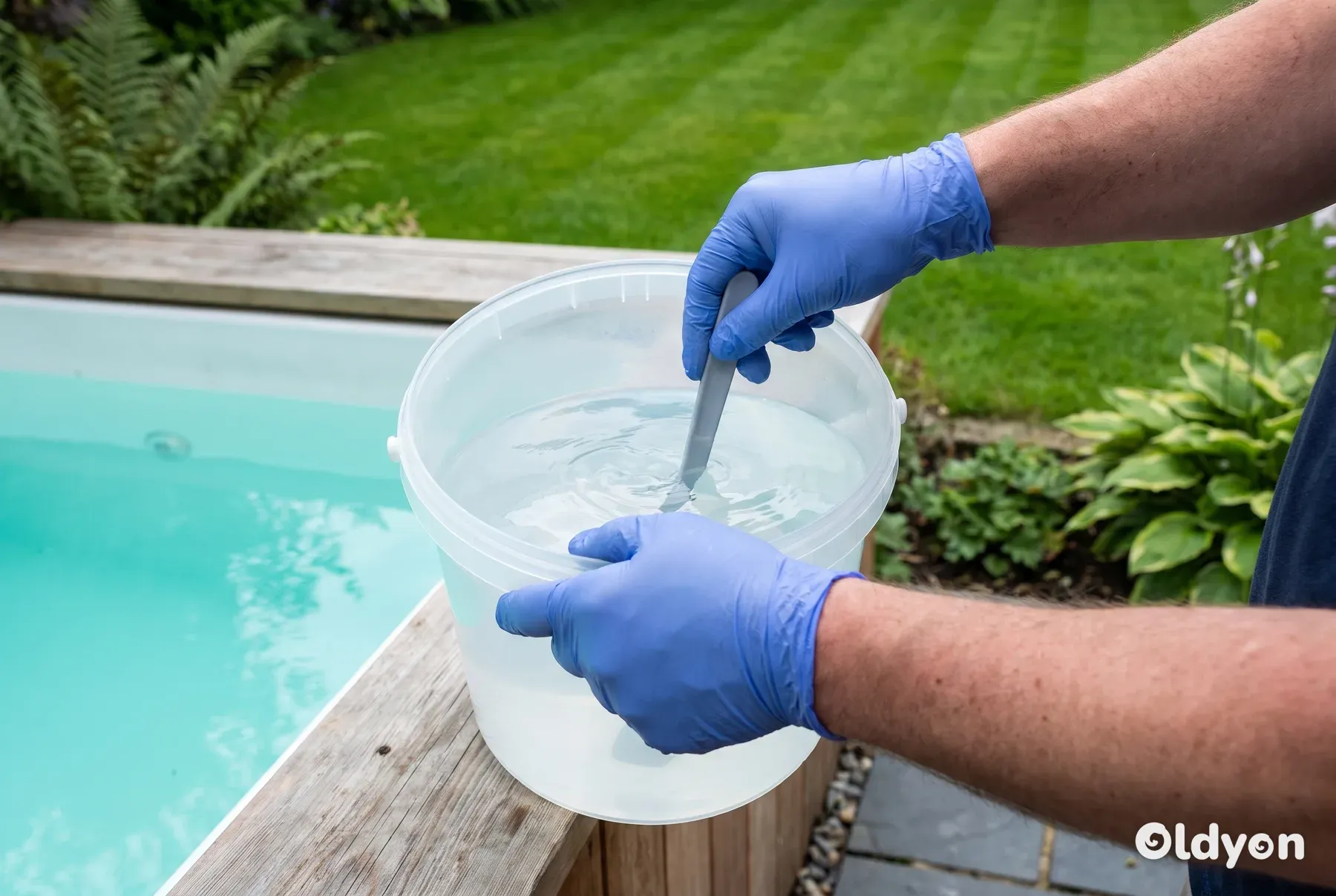 Hænder i handsker, der rører væske ud i en almindelig plastikspand med vand ved siden af et åbent spabad.
