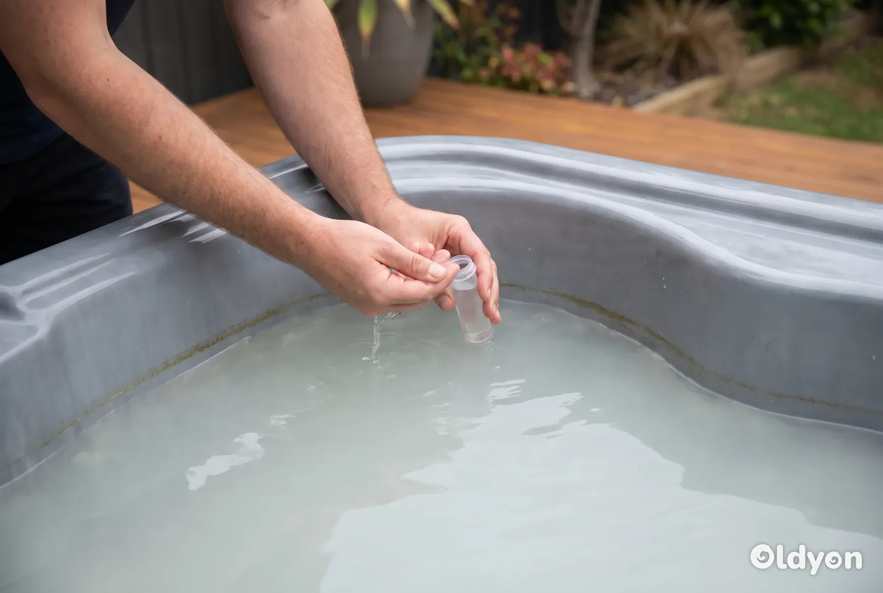 Delle mani prelevano un campione di acqua torbida della vasca idromassaggio in una fiala di plastica trasparente per analizzarla.