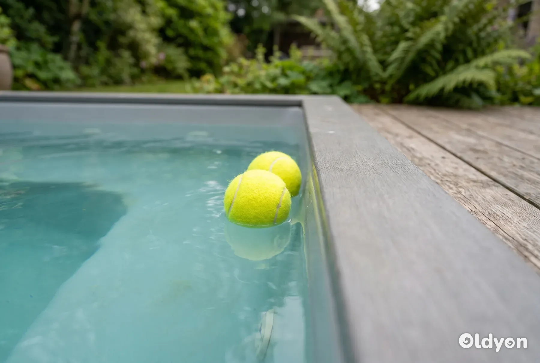 To gule tennisballer flyter på overflaten av litt uklart boblebadsvann.