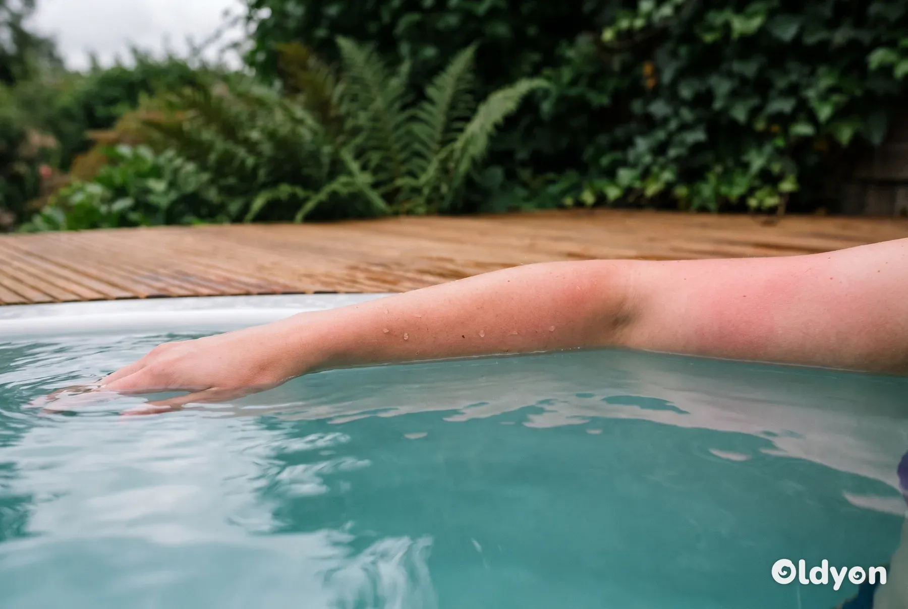 Et nærbilde av en underarm nedsenket i varmt vann i et boblebad, som viser en lett, naturlig rødme.