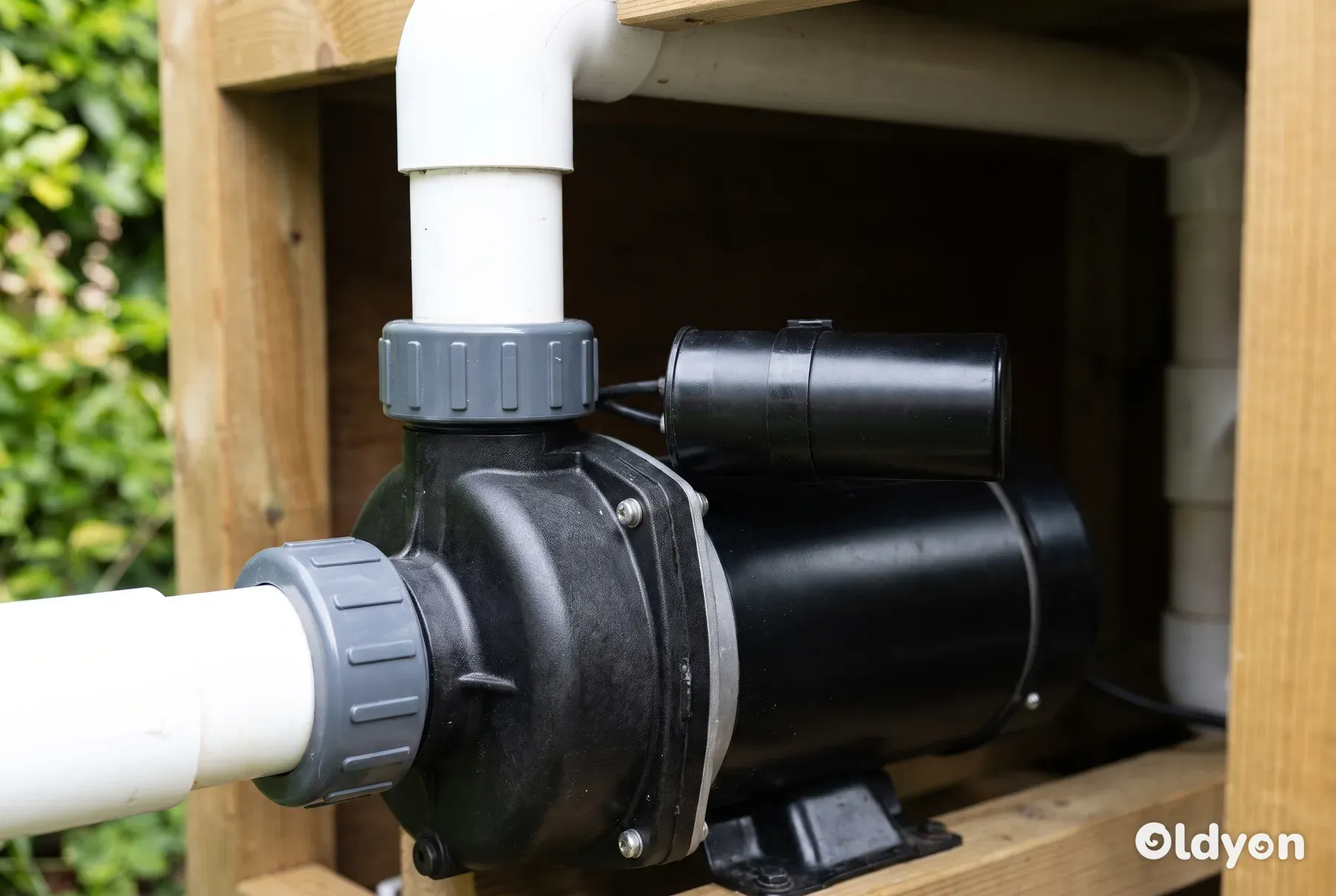Et detaljeret billede af en sort pumpemotor til et udespa og dens påmonterede cylindriske startkondensator.