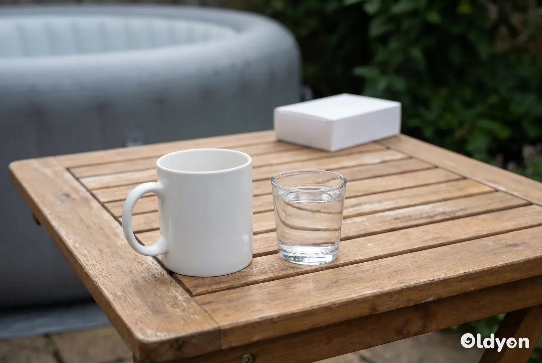 Et kaffekrus står i god afstand fra en neutral medicinæske på et havebord af træ.