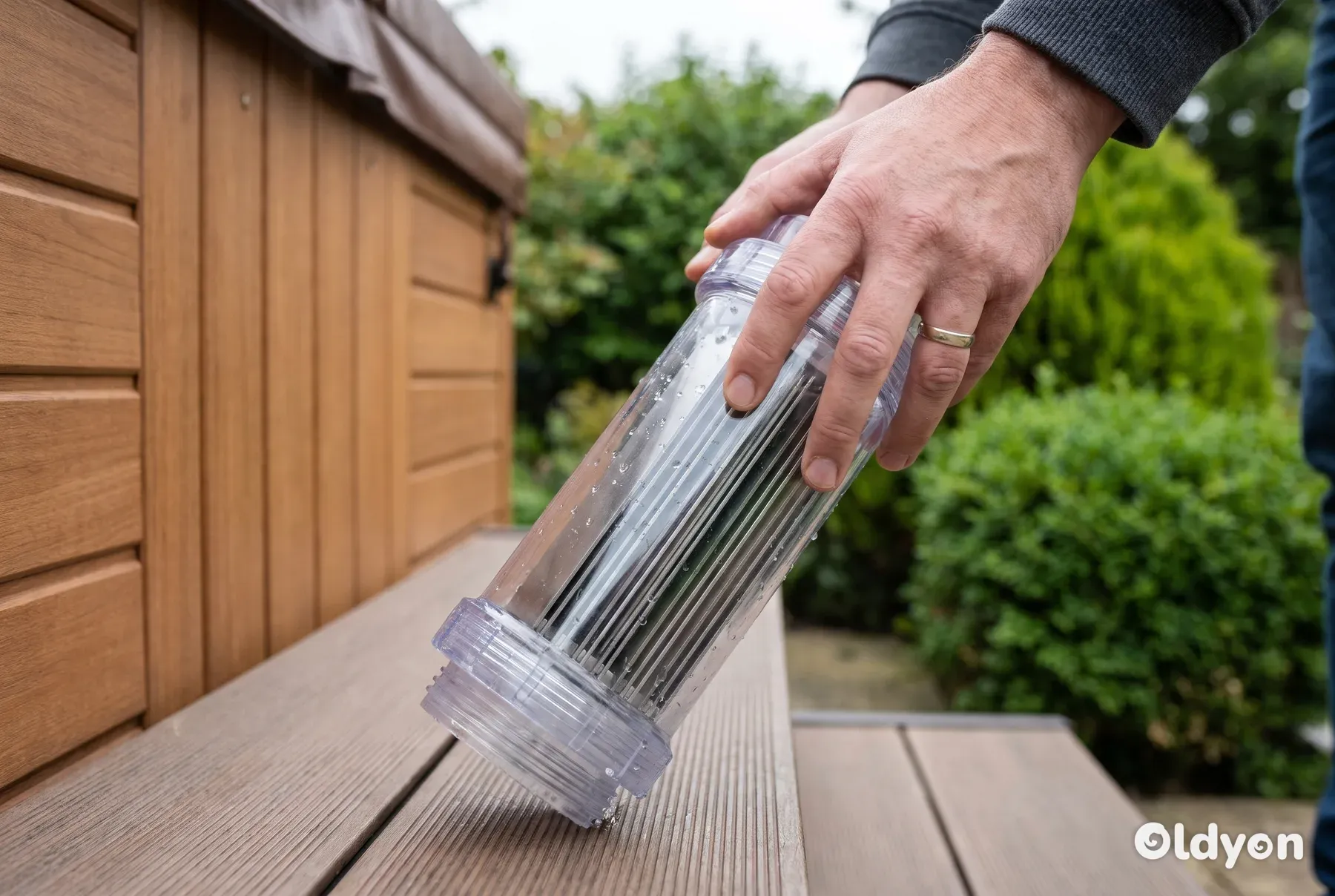 Een persoon houdt een doorzichtige zoutcel van een hottub vast, waarop de interne titanium platen te zien zijn.