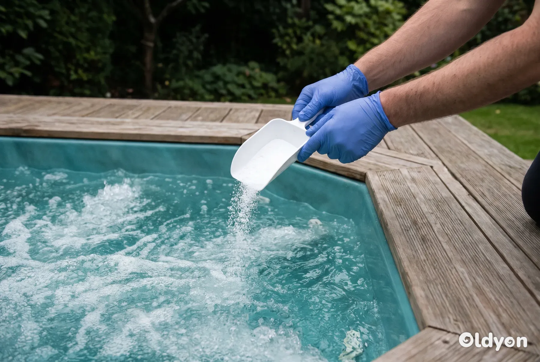 Handen met handschoenen strooien een schepje witte desinfectiekorrels in het bubbelende water van een hottub.